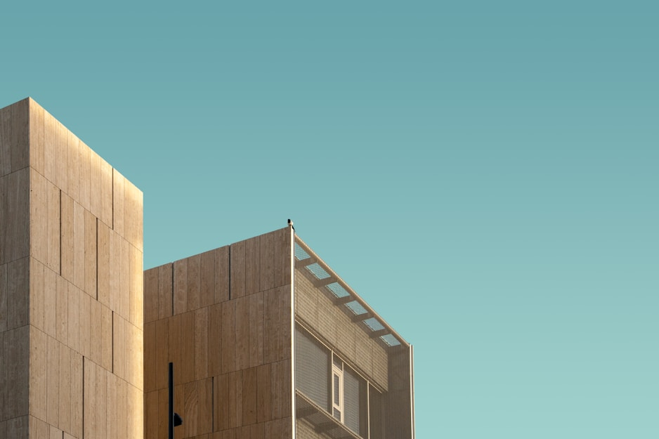 The top part of a square-roofed building against the blue-green sky.
